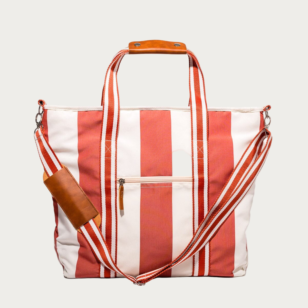 Red and white striped tote bag with brown leather accents on a white background